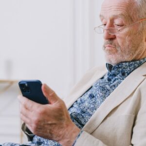 Hombre adulto mayor mirando su celular pensativo
